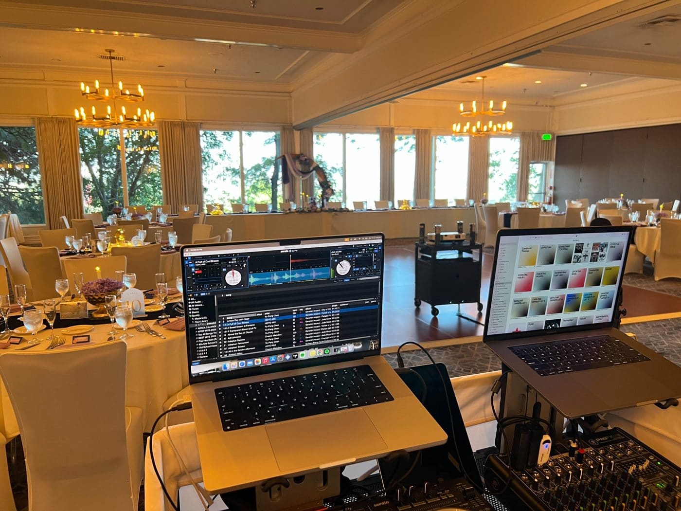 Professional DJ setup with laptops and mixing equipment in elegant ballroom with dining tables