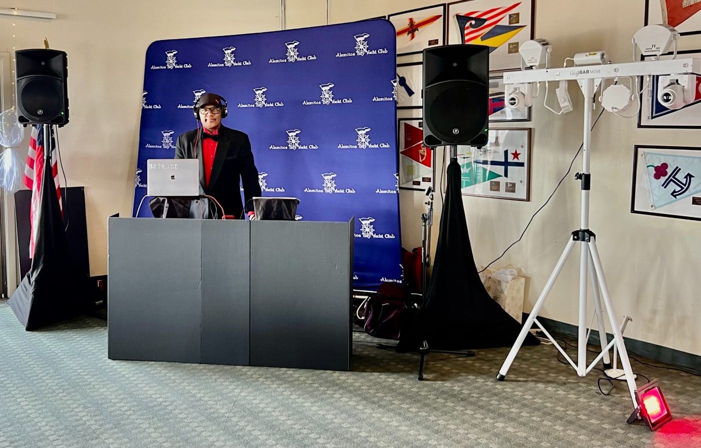 Man in blazer and red bow tie at podium with laptop during Hamilton Yacht Club event