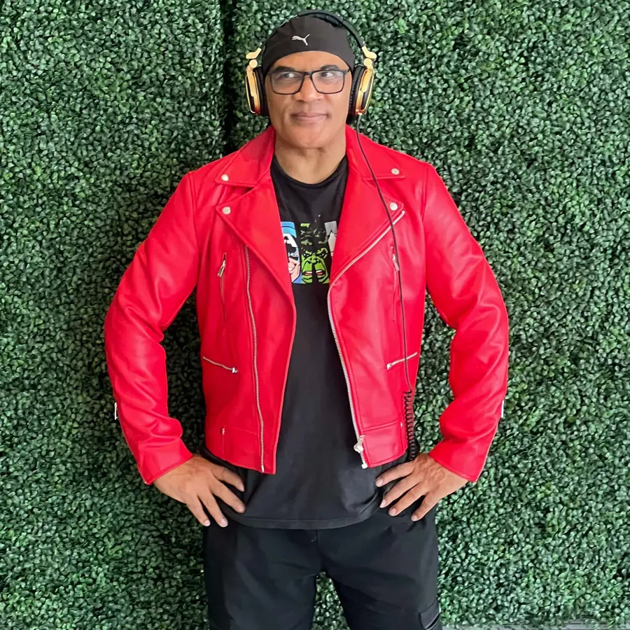 Man wearing red leather jacket and headphones against green wall backdrop